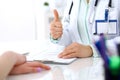 Doctor showing Ok sign with thumb up to patient while sitting at the desk in hospital office, close-up of human hands