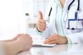 Doctor showing Ok sign with thumb up to patient while sitting at the desk in hospital office, close-up of human hands