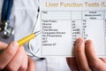 Doctor showing to patient or colleague on liver function test result LFT, standing in white medical coat. Concept photo to illustr