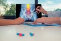 Doctor showing a x-ray of hips with pain in the spine on a laptop to a woman patient. Pills on the desk Royalty Free Stock Photo
