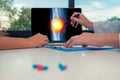 Doctor showing a x-ray of leg with pain in a knee on a laptop to a woman patient. Pills on the desk Royalty Free Stock Photo