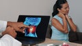 Doctor showing x-ray of pain in the neck on a laptop with woman patient. Migraine Headache illness