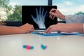 Doctor showing a x-ray of a right hand on a laptop to a woman patient. Pills on the desk. Osteoarthritis concept