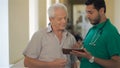 Doctor shows something on his tablet to senior man