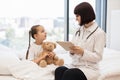 Doctor sitting on bed next to sick girl with tablet in hands Royalty Free Stock Photo