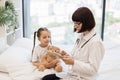 Doctor sitting on bed next to sick girl with tablet in hands Royalty Free Stock Photo