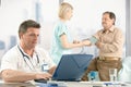 Doctor sitting at desk, nurse examining patient.