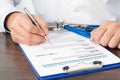 Doctor sitting at his desk with a stethoscope and writing something on a sheet Royalty Free Stock Photo