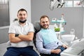 Doctor is sitting next to satisfied patient in dental chair