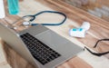 Doctor sitting at office desk and working on his laptop with medical equipment all around, top view Royalty Free Stock Photo