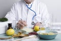 Doctor sitting at the table. Many ingredients for alternative medicine.Dried berries,herbs,lemons and diffirent portions of natura