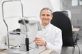 Doctor smiling, posing with modern eye test machine. Royalty Free Stock Photo