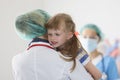 Doctor stands with his back and holds in his arms little frightened girl