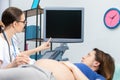 A lady doctor shows a pregnant patient her unborn baby on the ultrasound screen. Gynecology office. Royalty Free Stock Photo