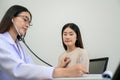 Doctor with stethoscope in hand Doctor checking heart rate listening to chest of young female patient with stethoscope in clinic Royalty Free Stock Photo