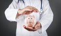 Doctor with stethoscope holding piggy bank Royalty Free Stock Photo