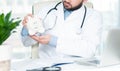 Doctor with stethoscope holding piggy bank. Royalty Free Stock Photo