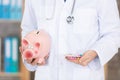 doctor with stethoscope holding piggy bank and pills Royalty Free Stock Photo