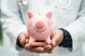 Doctor with Stethoscope holding piggy bank for saving money health care cost, medical financial Royalty Free Stock Photo