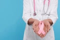 Doctor with stethoscope holding pink ribbon on light blue background, closeup and space for text. Breast cancer awareness Royalty Free Stock Photo