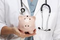 Doctor with Stethoscope Holds Piggy Bank Royalty Free Stock Photo