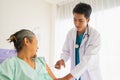 Doctor with stethoscope using injecting syringe to elderly patient man on bed looking to syringe. Royalty Free Stock Photo