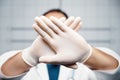 Doctor stops making prohibition signs. Doctor holding crossed hands in gloves