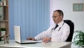 Doctor studying treatment methods on laptop, looking for innovative approach