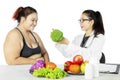 Doctor suggesting her fat patient to eat vitamins Royalty Free Stock Photo