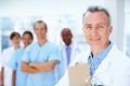 Doctor supported by his staff. Confident doctor with medical staff in background. Royalty Free Stock Photo