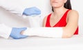 Doctor surgeon establishes a gypsum bandage and a tight bandage on the hand of a girl with an offset fracture, background