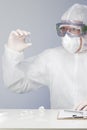 Doctor with surgical mask and protective clothing looking at a vaccine