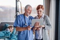 Doctor with tablet talking to mother of small hospitalized girl in hospital. Royalty Free Stock Photo