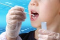 Doctor takes a cotton bud from childÃ¢â¬â¢s mouth to analyze the saliva, mucous membrane for DNA tests, COVID-19, to determine