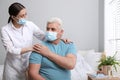 Doctor taking care of senior man with mask at nursing home Royalty Free Stock Photo