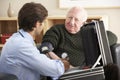 Doctor taking senior man's blood pressure at home Royalty Free Stock Photo