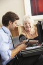 Doctor taking senior woman's blood pressure at home Royalty Free Stock Photo