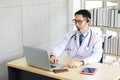 Asian doctor talking with patient or co-worker through online video chat with computer in hospital