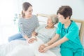 Doctor talking to elderly patient lying in bed while patient`s daughter sitting beside her on bed in hospital Royalty Free Stock Photo