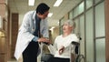 Doctor talking to elderly woman patient in wheelchair before surgery at hospital hallway Royalty Free Stock Photo