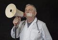 Doctor with tape across his mouth trying to shout into a megaphone Royalty Free Stock Photo