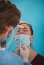 Doctor is testing for coronavirus. A young lady is waiting for a swab from the nose. Collection center. Global pandemic.