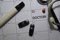 Doctor text on white calendar background. Reminder or schedule concept