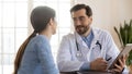 Doctor therapist consulting patient at meeting, using computer tablet