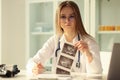 Doctor therapist examining result of ultrasound examination of abdominal cavity in clinic