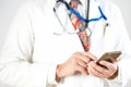 A doctor in a tie and with a stethoscope is holding a smartphone Royalty Free Stock Photo