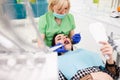 Dentist treat patient teeth. Female patient during the treatment of teeth by the dentist watches the process in the