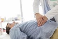 Doctor treating stomach of patient in examination room Royalty Free Stock Photo