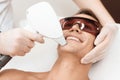 The doctor treats the face of a man with a modern laser epilator. The man lies and smiles.