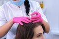 Doctor trichologist examines woman patient`s hairs using trichoscope in clinic.